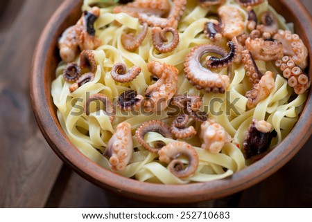 Close-up of tagliatelle with sliced octopus, selective focus