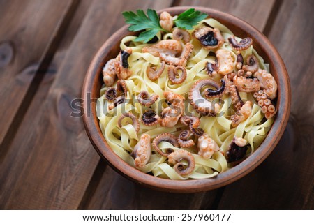 Tagliatelle with sliced octopuses in a ceramic bowl, studio shot