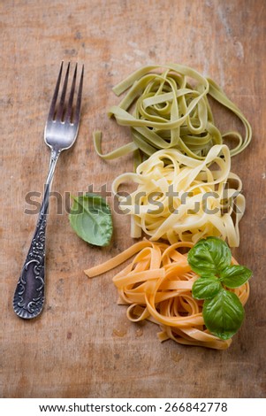 Pasta of italian flag colors on a rustic wooden background