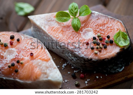 Close-up of two fresh salmon steaks with sea salt, pepper and basil leaves