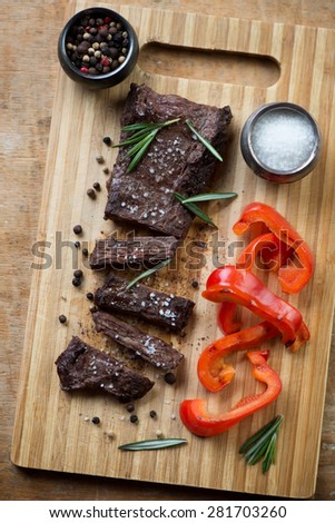 Wooden cutting board with well-done grilled machete beef steak, above view