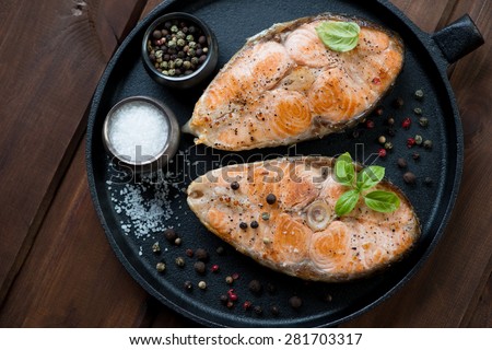 Frying pan with two roasted salmon steaks, view from above