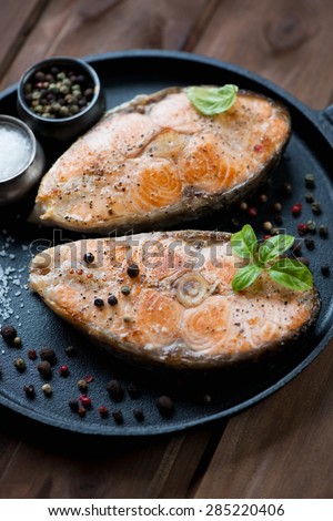 Close-up of roasted salmon steaks with spices in a frying pan, selective focus
