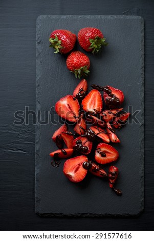 Stone slate dish with strawberries and chocolate, above view, vertical shot