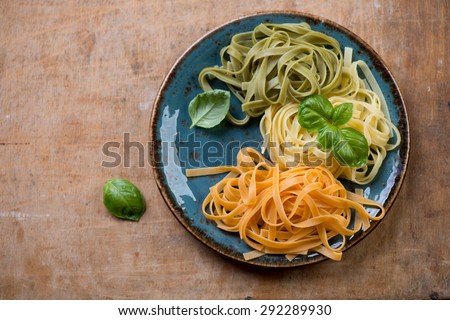 Turquoise plate with pasta of italian flag colors, above view
