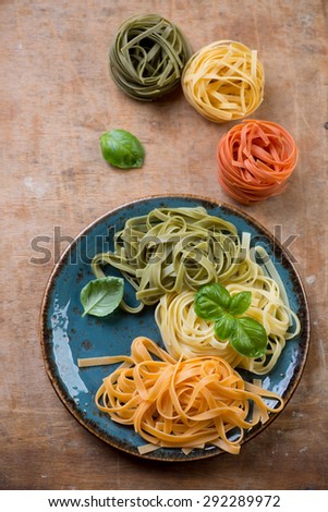 Top view of tagliatelle of italian flag colors with basil leaves