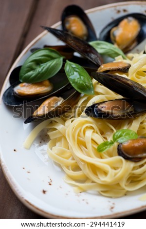 Close-up of boiled mussels with pasta and basil, selective focus