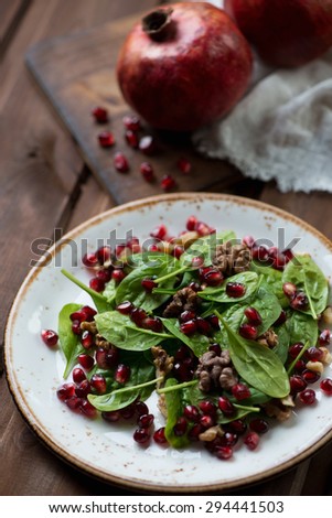 Salad with fresh spinach leaves, pomegranate seeds and walnuts