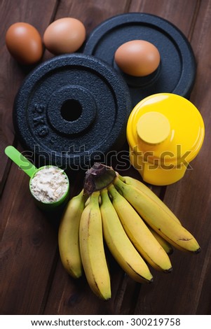 Protein, shaker, weight plates, eggs and bananas, above view