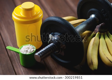 Dumbbell, scoop with protein, shaker and bananas, close-up