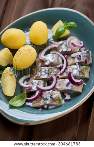 Sliced herring fillet with boiled potato, red onion and basil