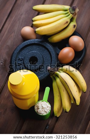 Protein scoop, plastic shaker, weight plates, hen eggs and bananas