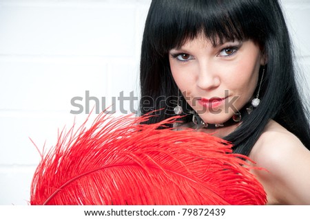 Sexual dark-haired woman with red feather, close-up