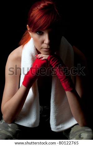 Serious young woman in boxing-bandage meditating before the fight