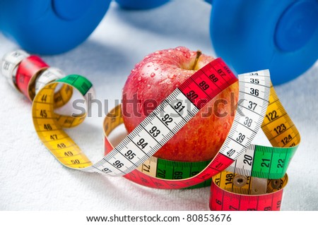 Red apple with a tape-line and dumbbells