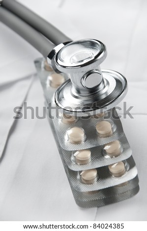 Stethoscope on top of a stack of sealed blister packs full of tablets