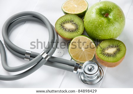 Studio shot of fresh fruits and stethoscope on doctor\'s smock. Healthy eating concept