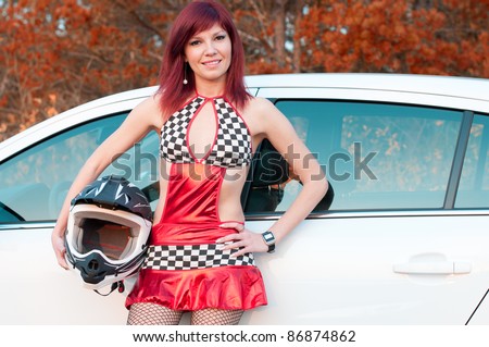 Smiling young caucasian woman with a helmet by her car. Street racing concept