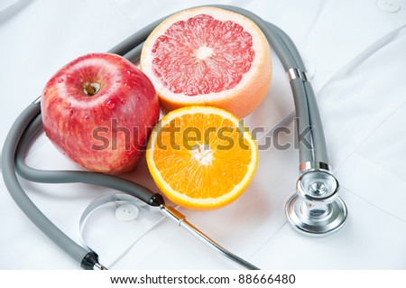 Healthy life-style concept with stethoscope and fresh fruits on doctor\'s smock