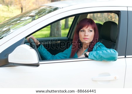 Confident female redheaded driver sitting in a car outdoors