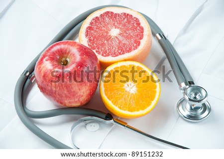 Various fresh fruits and stethoscope on doctor\'s smock