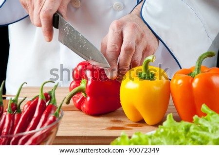 Food preparation: chef cutting bell peppers, studio shot