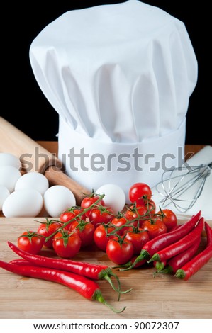 Fresh tomatoes and chili peppers, chef\'s hat and kitchen utensils