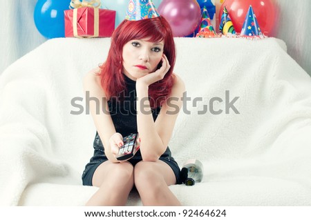 Sad red-haired party woman sitting at home and watching TV