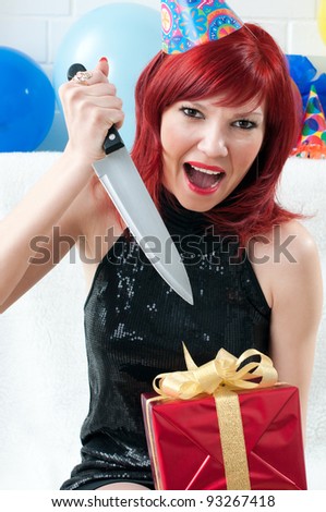 Emotional red-haired party woman screaming and opening a gift box with a kitchen knife