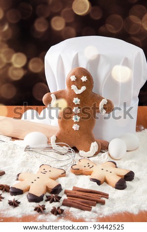 Gingerbread cookies, chef's toque and food ingredients over glittery gold background