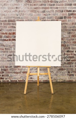 Easel with blank canvas on a brick wall background
