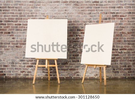 Pair of Easel with blank canvas on a brick wall background