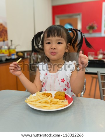 Little girl eating french fries at fast food restaurant
