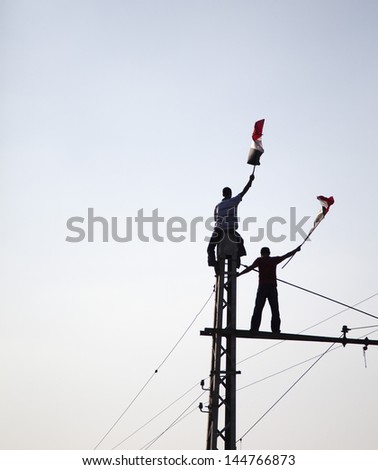 Cairo, Egypt - July 1: Two Young Egyptians Protesting On Top Of Tramway Pole Holding Egyptian Flag Near El-Etehadeya Palace During &Quot;June 30&Quot; Protests Against Mohamed Morsy. Cairo - July 1, 2013