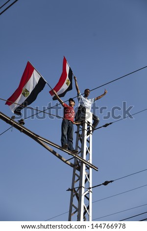 CAIRO, EGYPT - JULY 1: Two young Egyptians protesting on top of tramway pole holding Egyptian flag near El-Etehadeya palace during \