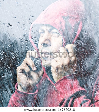 Portrait of a middle age man talking in the phone in rain in a red hood