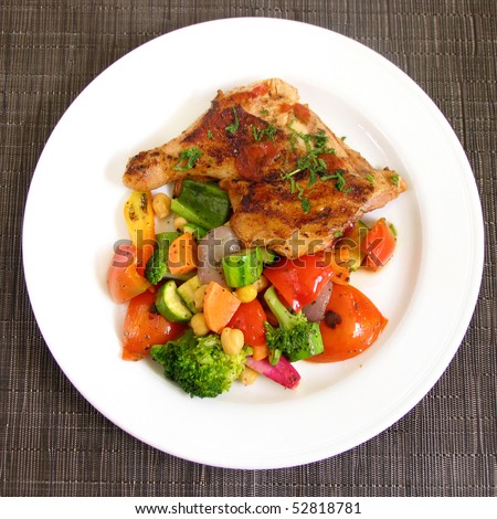 Grilled chicken on a white plate with vegetables on the background.