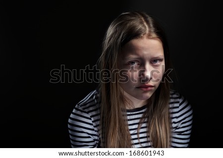 Dark portrait of a crying teen girl, studio shot