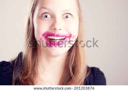 Happy teen girl making funny faces with pomade on lips and cheeks