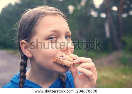 Happy teen girl walking in the forest in the rain and eating