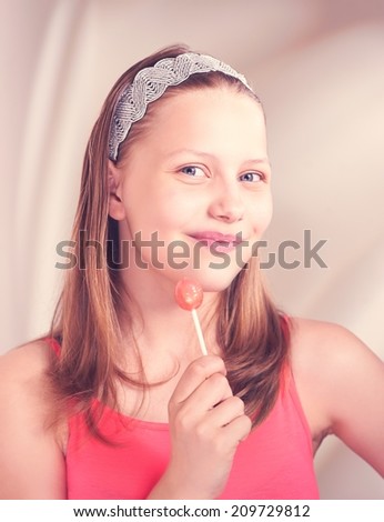 Beautiful happy teen girl smiling and holding lollipop