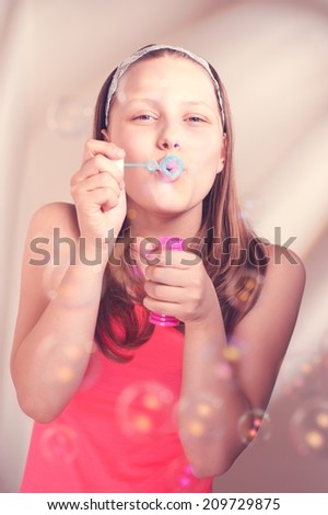 Beautiful happy teen girl blowing soap bubbles