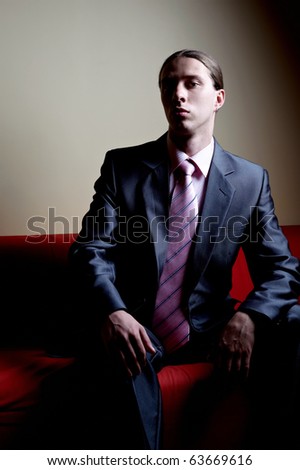 Contrasty portrait of handsome serious man on sofa