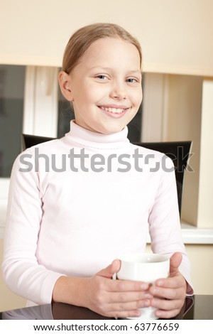 Portrait of cute cheerful little girl with big white cup. Drinking tea.