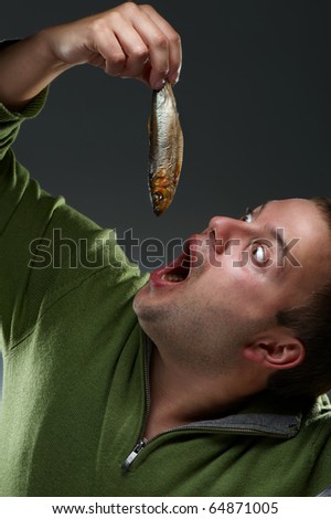 Hungry corpulent man with open mouth staring at a fish