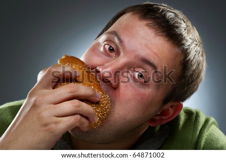 Hungry corpulent man eating white bread. Mouth full of bread