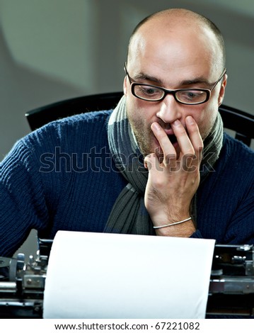 Old fashioned bald writer in glasses writing book on a vintage typewriter