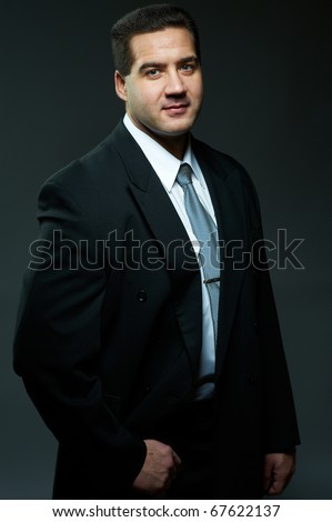 Dark portrait of handsome stylish young man in black suit, studio shot