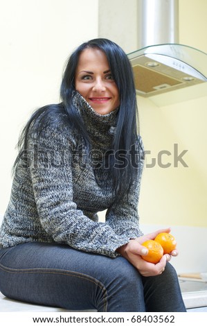 Young pretty woman sitting on a table with tangerine in hand