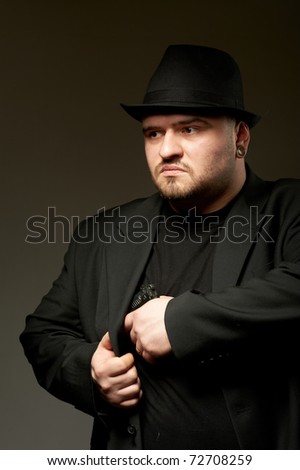 Dangerous man in black suite and hat with gun.